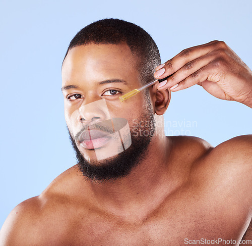 Image of Man, portrait or face oil in studio, aesthetic skincare or beauty dermatology on blue background. Serious black male model, facial cosmetics or dropper of hyaluronic acid, collagen or vitamin c serum