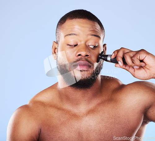 Image of Man, shave and worry with face razor for hair removal, aesthetic skincare and facial cleaning in studio. Scared black male model shaving beard with blade, trimmer or cosmetic tool on blue background