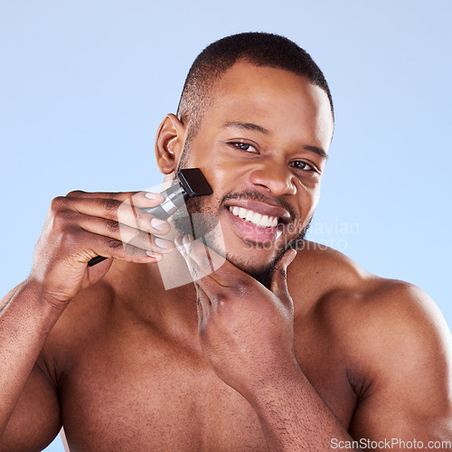 Image of Portrait, man and shave with razor for hair removal, aesthetic skincare and facial cleaning in studio. Happy black male model shaving beard on face with blade, trimmer and cosmetic tool on background