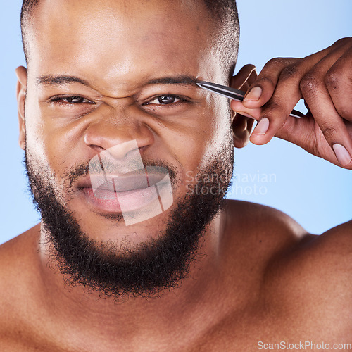 Image of Wellness, tweezers and portrait of a man in a studio for grooming his eyebrows for facial epilation. Beauty, hygiene and young male model with face hair removal treatment isolated by blue background.