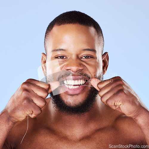 Image of Portrait, black man and floss teeth in studio, healthy dental care or gum gingivitis. Face of male model cleaning mouth with oral thread for fresh breath, tooth cosmetics or plaque on blue background