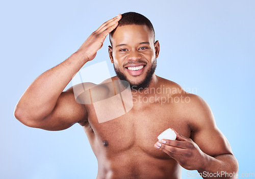 Image of Beauty, portrait and a black man with cream for hair care, shine and moisture on a blue background. Happy, wellness and an African person or model with gel for growth isolated on a studio backdrop