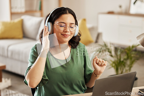 Image of Laptop, music and streaming with a woman in her home, listening to the radio in the living room to relax. Computer, audio and headphones with a young female student in her house for education