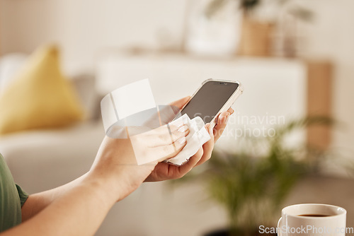 Image of Closeup of a woman cleaning her phone with paper to prevent germs, dirt or dust bacteria at home. Hygiene, technology and female person wipe her cellphone to sanitize her screen in the living room.