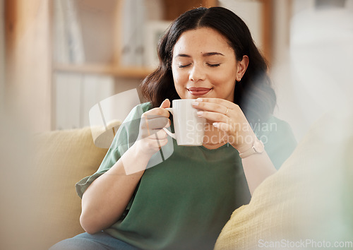 Image of Tea, relax and smile with a woman in her home, sitting on a sofa in the living room enjoying a beverage. Peace, quiet and eyes closed with a happy young female person drinking coffee in her house