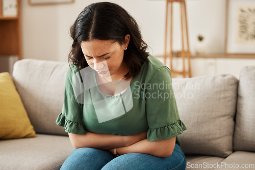 Image of Stress, stomach pain and woman on a sofa with menstruation, gas or constipation, pms or nausea at home. Gut health, anxiety and lady with tummy ache in living room from ibs, bloated or endometriosis