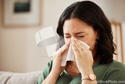 Image of Tissue, blowing nose and woman in a living room with flu, cold and hay fever, crisis or viral infection in her home. Sneezing, allergies and person with health risk in a lounge or coughing illness