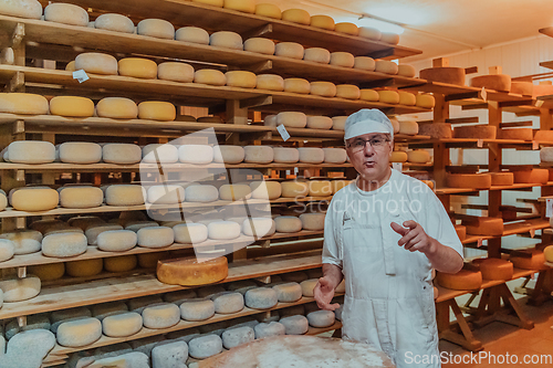 Image of A worker at a cheese factory sorting freshly processed cheese on drying shelves