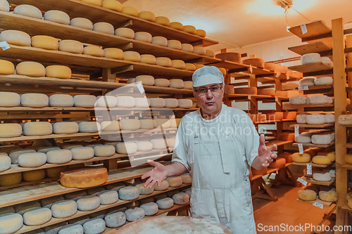 Image of A worker at a cheese factory sorting freshly processed cheese on drying shelves