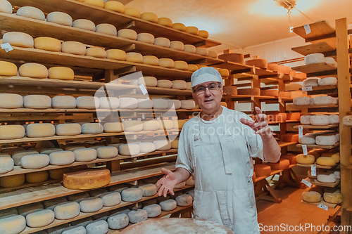 Image of A worker at a cheese factory sorting freshly processed cheese on drying shelves