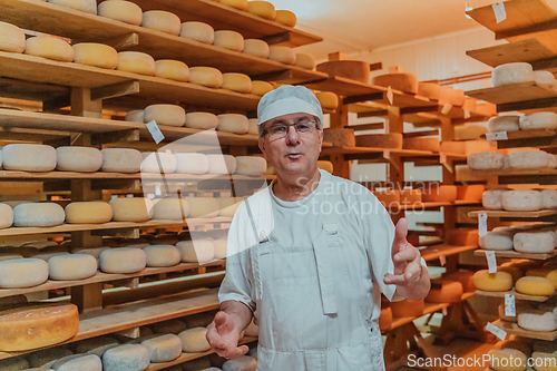 Image of A worker at a cheese factory sorting freshly processed cheese on drying shelves