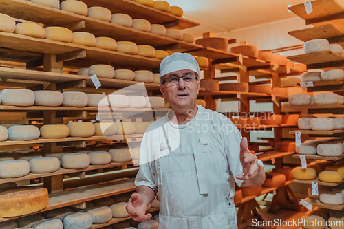 Image of A worker at a cheese factory sorting freshly processed cheese on drying shelves