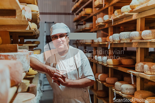 Image of A worker at a cheese factory sorting freshly processed cheese on drying shelves