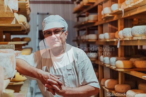 Image of A worker at a cheese factory sorting freshly processed cheese on drying shelves