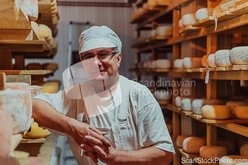 Image of A worker at a cheese factory sorting freshly processed cheese on drying shelves