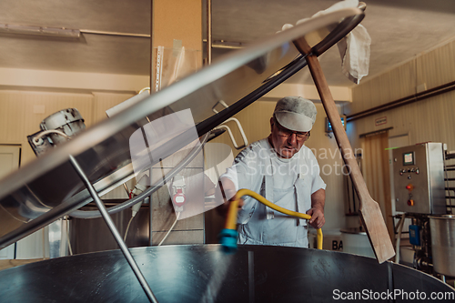 Image of A cheese makser working in the industry on various machines with the help of which cheese is processed. Small business concept