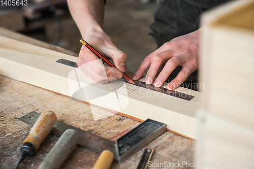 Image of The worker makes measurements of a wooden board