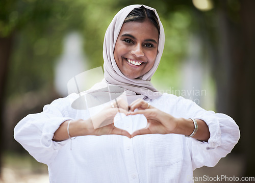 Image of Hands in heart, park and portrait of Muslim woman for support, love symbol and care outdoors. Happy, emoji and face of Islamic female person with hijab and hand sign for kindness or peace in nature