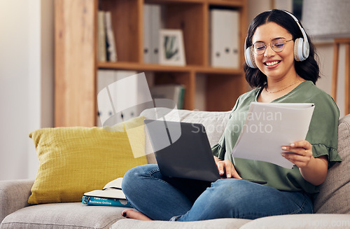 Image of Laptop, documents and remote work with a freelance woman working online for a business startup. Computer, music and headphones with a happy young female entrepreneur reading information in her home