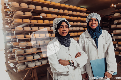 Image of Arab business partners checking the quality of cheese in the industry and enter data into a laptop. Small business concept