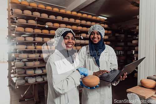 Image of Arab business partners checking the quality of cheese in the industry and enter data into a laptop. Small business concept