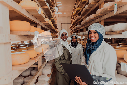 Image of Arab business partners checking the quality of cheese in the industry and enter data into a laptop. Small business concept