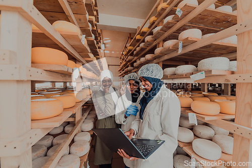 Image of Arab business partners checking the quality of cheese in the industry and enter data into a laptop. Small business concept