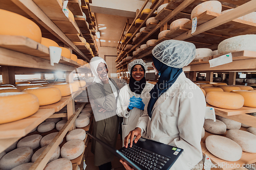 Image of Arab business partners checking the quality of cheese in the industry and enter data into a laptop. Small business concept