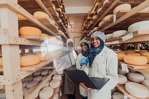 Image of Arab business partners checking the quality of cheese in the industry and enter data into a laptop. Small business concept