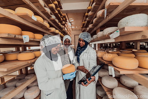 Image of Arab business partners checking the quality of cheese in the industry and enter data into a laptop. Small business concept