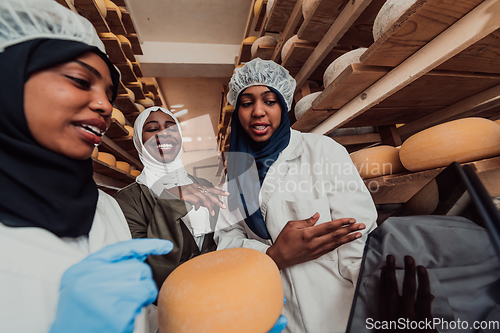 Image of Arab business partners checking the quality of cheese in the industry and enter data into a laptop. Small business concept