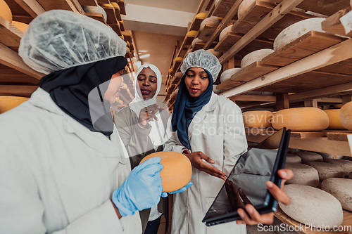 Image of Arab business partners checking the quality of cheese in the industry and enter data into a laptop. Small business concept