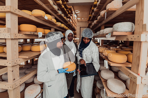 Image of Arab business partners checking the quality of cheese in the industry and enter data into a laptop. Small business concept