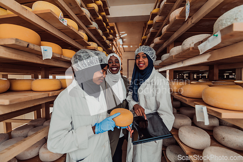 Image of Arab business partners checking the quality of cheese in the industry and enter data into a laptop. Small business concept