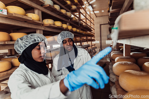 Image of Arab business partners checking the quality of cheese in the industry and enter data into a laptop. Small business concept