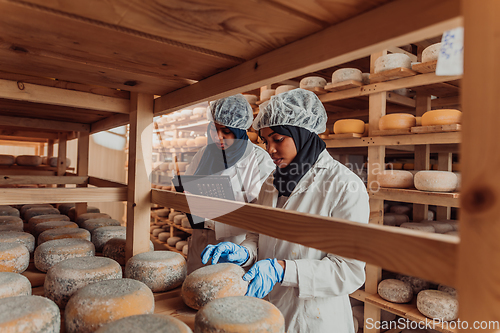 Image of Arab business partners checking the quality of cheese in the industry and enter data into a laptop. Small business concept