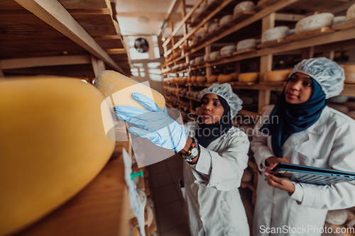 Image of Arab business partners checking the quality of cheese in the industry and enter data into a laptop. Small business concept