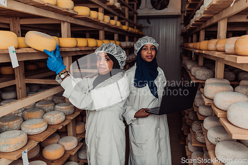 Image of Business of a Muslim partners in a cheese warehouse, checking the quality of cheese and entering data into laptop