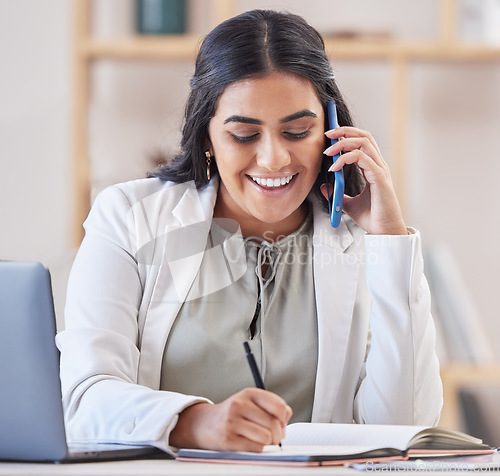 Image of Business woman, phone call and writing in office for networking, schedule and communication. Happy indian female worker talking on smartphone, planning agenda and calendar administration in notebook