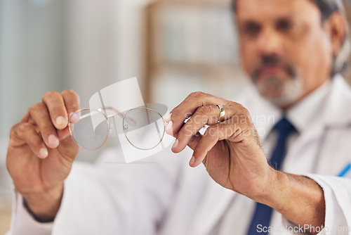 Image of Optometrist, man and glasses in hand for vision or eyesight or prescription lens for worker. Doctor, closeup and frames in workplace with eyewear for wellness or focus with medical expert for care.