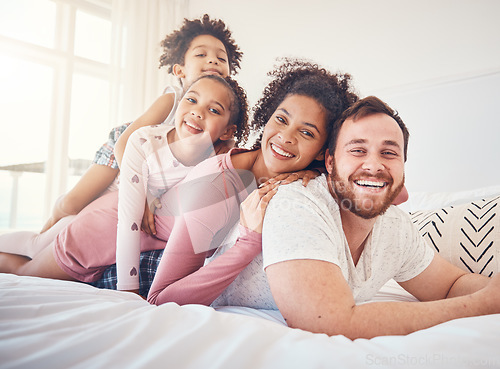 Image of Happy family, portrait and relax on a bed, bond and having fun on the weekend in their home together. Interracial, love and face of playful children with parents in a bedroom, smile and playing games