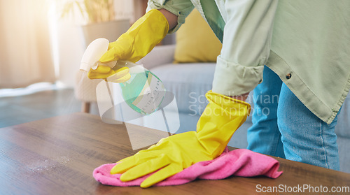 Image of Woman, hands and cleaning table with spray for housekeeping, hygiene or bacteria removal at home. Female person or cleaner spraying chemical bottle for germs, dirt and wiping wooden desk or furniture