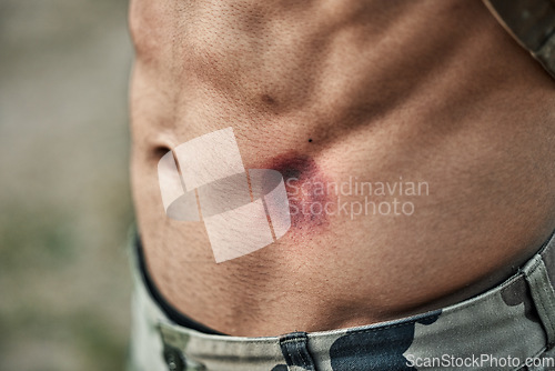 Image of Paintball injury, stomach bruise and man in closeup with pain, shooting or accident for outdoor war games. Abdomen, emergency and wound in military training, zoom and battlefield for exercise in army