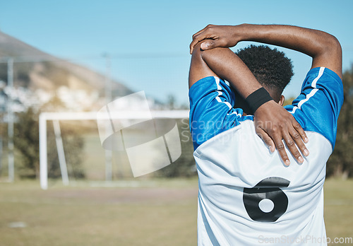 Image of Man, soccer and stretching arm in fitness commitment for match, game or training on grass field outdoors. Rear view of person or sports athlete in body warm up for healthy start or football practice