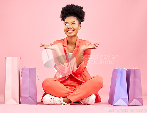 Image of Woman, shopping bag and smile on studio floor, idea or thinking for deal, sale or choice by pink background. African gen z girl, happy or decision for fashion, open palm or retail customer experience