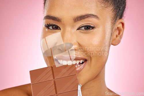 Image of Woman, chocolate and bite in studio portrait with smile, eating and skin glow for beauty by pink background. Girl, model and diet with sweets, snack or candy for cheat day, cosmetics and headshot