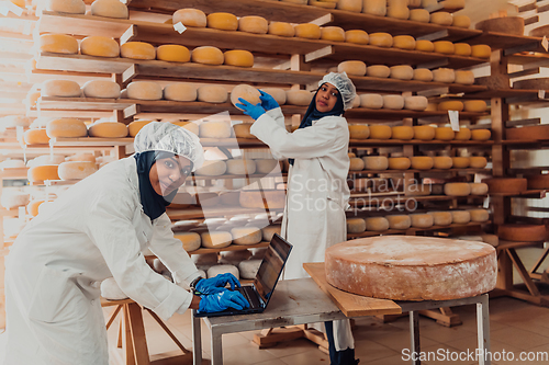 Image of Muslim business partners checking the quality of cheese in the modern industry