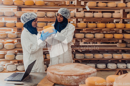 Image of Muslim business partners checking the quality of cheese in the modern industry