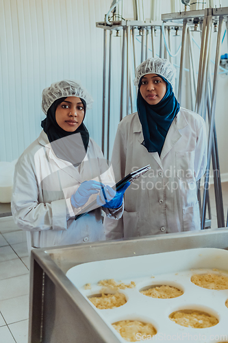 Image of Arab business partners checking the quality of cheese in the industry and enter data into a laptop. Small business concept