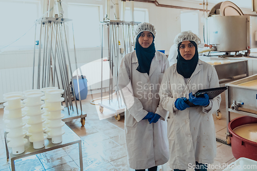 Image of Arab business partners checking the quality of cheese in the industry and enter data into a laptop. Small business concept